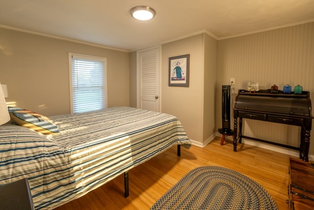 bedroom with light hardwood / wood-style floors, ornamental molding, and a closet