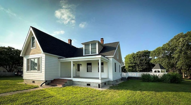 back of property with covered porch and a yard