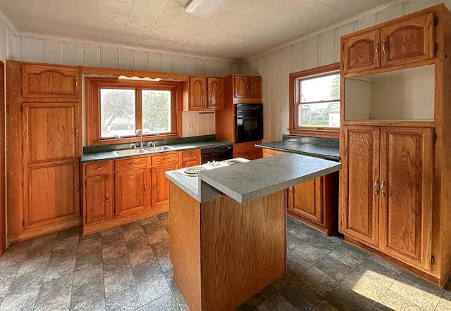 kitchen with black oven, sink, a kitchen island, and plenty of natural light