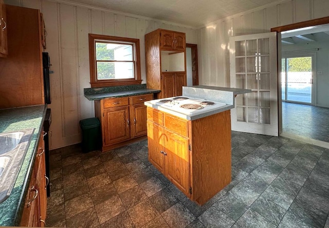 kitchen with white cooktop, a center island, a healthy amount of sunlight, and crown molding