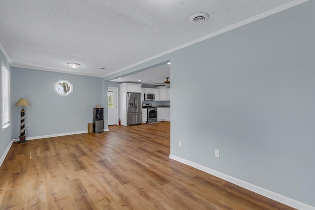 2920 Newmans Neck Rd, Heathsville, VA 22473 - unfurnished living room with ornamental molding, baseboards, ceiling fan, light wood finished floors, and a textured ceiling