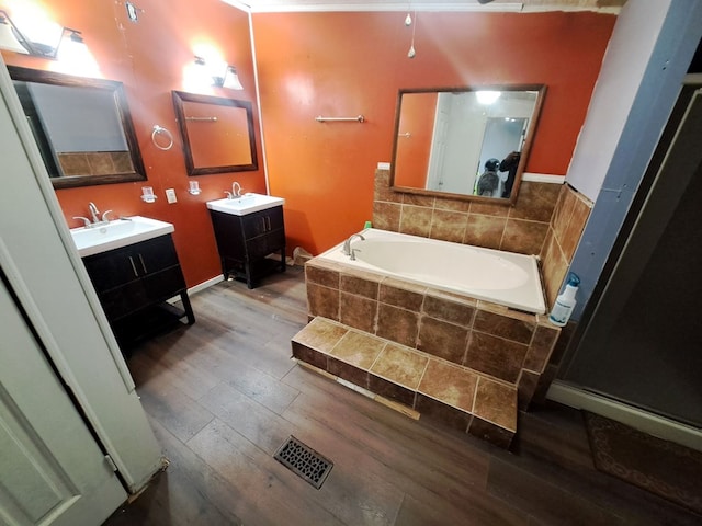 bathroom featuring hardwood / wood-style floors, vanity, and tiled tub