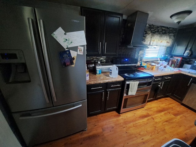 kitchen featuring stainless steel fridge, light wood-type flooring, stove, wall chimney exhaust hood, and dishwasher