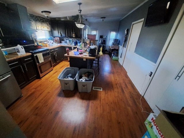 kitchen featuring light wood-type flooring, stainless steel range, extractor fan, decorative light fixtures, and a kitchen island