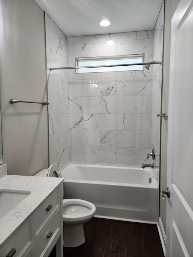 full bathroom with hardwood / wood-style floors, tiled shower / bath combo, toilet, and vanity