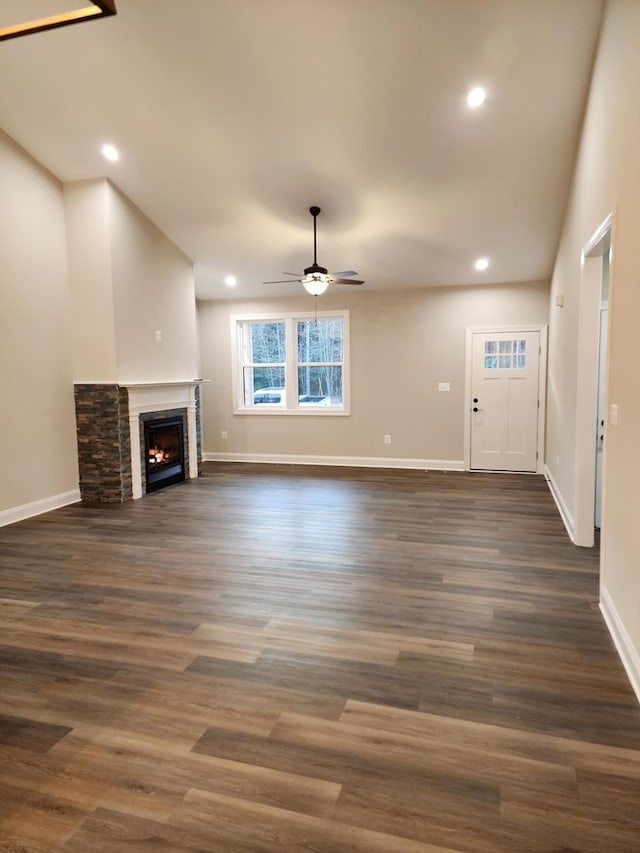 unfurnished living room featuring ceiling fan, a fireplace, and dark wood-type flooring