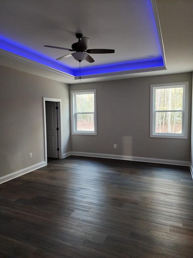 spare room with ceiling fan, dark hardwood / wood-style floors, and a raised ceiling