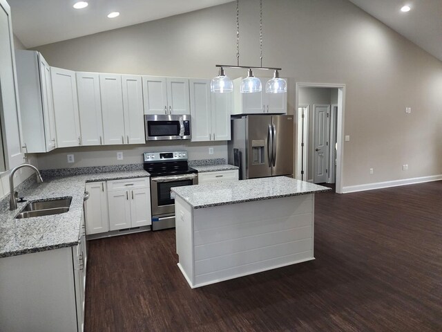 kitchen featuring appliances with stainless steel finishes, sink, white cabinets, a kitchen island, and hanging light fixtures