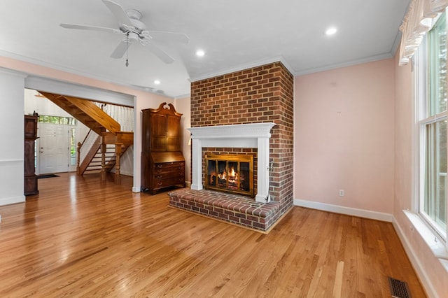 unfurnished living room featuring ceiling fan, a fireplace, light hardwood / wood-style floors, and ornamental molding