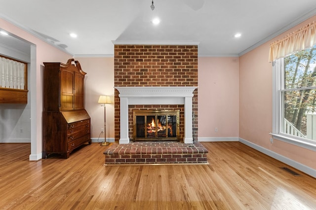 unfurnished living room featuring light hardwood / wood-style floors, crown molding, and a brick fireplace