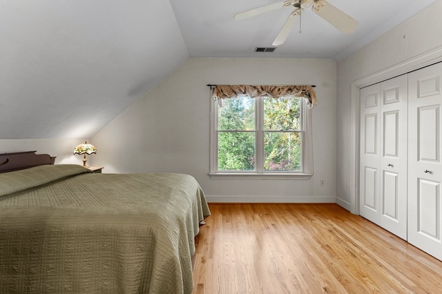 unfurnished bedroom featuring vaulted ceiling, a closet, light hardwood / wood-style flooring, and ceiling fan