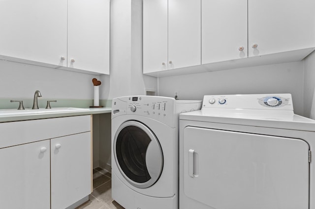 washroom with cabinets, light tile patterned flooring, washer and dryer, and sink