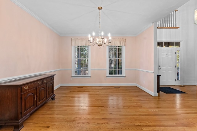 unfurnished dining area featuring an inviting chandelier, ornamental molding, and light wood-type flooring