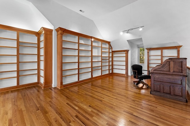 home office with rail lighting, light hardwood / wood-style floors, and lofted ceiling