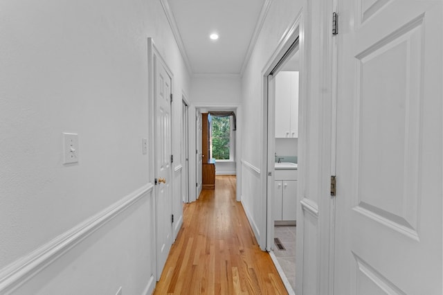 corridor with sink, light wood-type flooring, and crown molding