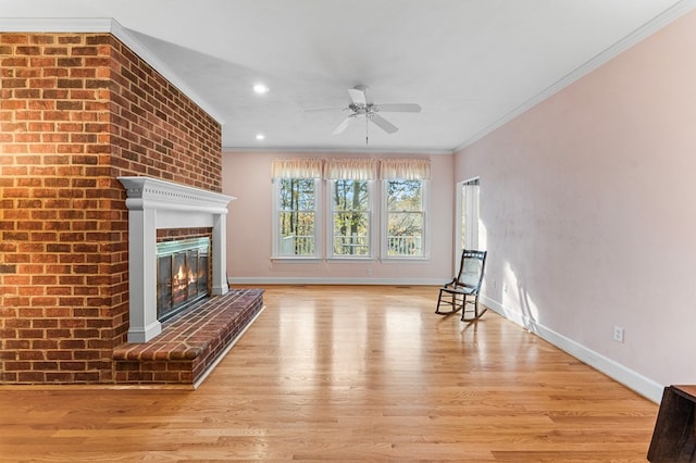 unfurnished room featuring ceiling fan, light hardwood / wood-style flooring, crown molding, and a brick fireplace