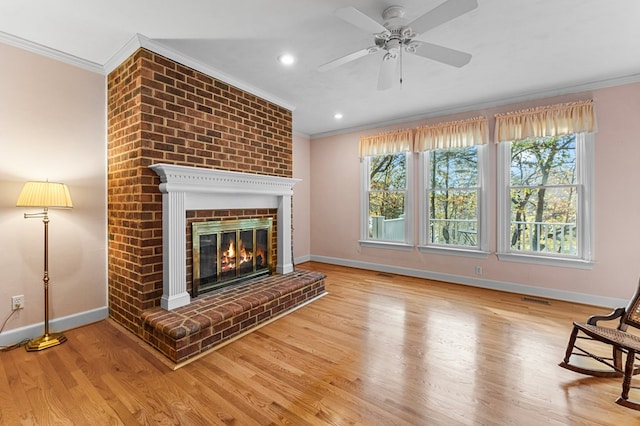 unfurnished living room with ceiling fan, crown molding, wood-type flooring, and a fireplace