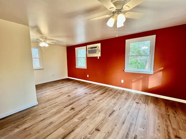 empty room with ceiling fan, an AC wall unit, and light hardwood / wood-style flooring