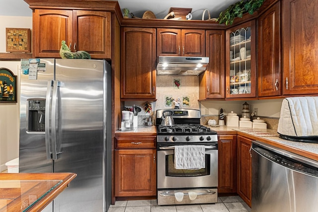 309 Nomini Bay Dr, Montross, VA 22520 - kitchen featuring stainless steel appliances, under cabinet range hood, tile counters, glass insert cabinets, and light tile patterned flooring