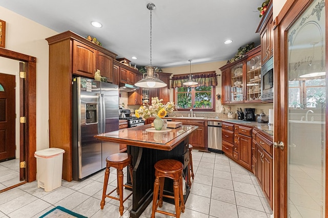309 Nomini Bay Dr, Montross, VA 22520 - kitchen featuring appliances with stainless steel finishes, light tile patterned flooring, a kitchen island, a breakfast bar, and glass insert cabinets