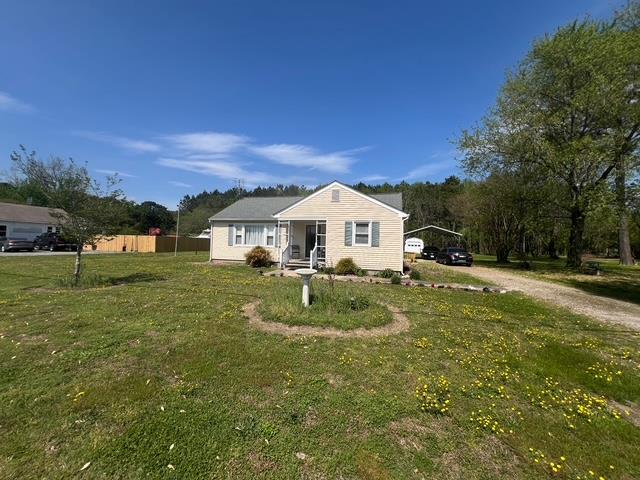 bungalow-style home with fence, a carport, dirt driveway, and a front lawn