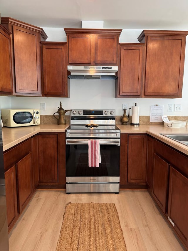 230 Roseneath Ave, Kilmarnock, VA 22482 - kitchen featuring stainless steel electric stove, under cabinet range hood, light wood finished floors, white microwave, and light countertops