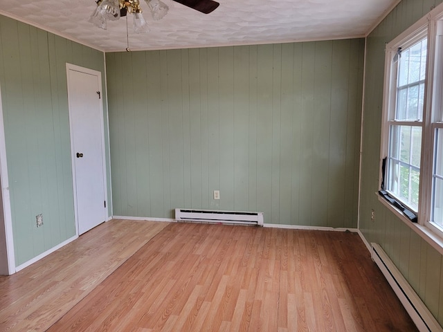 unfurnished room with a baseboard heating unit, ceiling fan, baseboards, light wood-style flooring, and a baseboard radiator