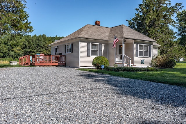 view of front of house with a deck, driveway, and a chimney