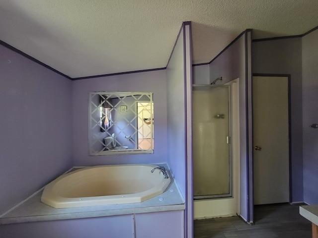 159 Dirt Bridge Rd, Topping, VA 23169 - bathroom with a stall shower, a bath, a textured ceiling, and wood finished floors