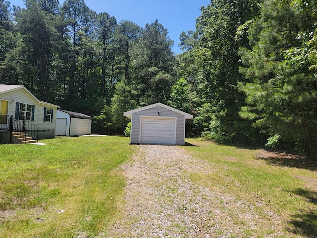 159 Dirt Bridge Rd, Topping, VA 23169 - view of green lawn featuring an outdoor structure, a detached garage, driveway, and a view of trees