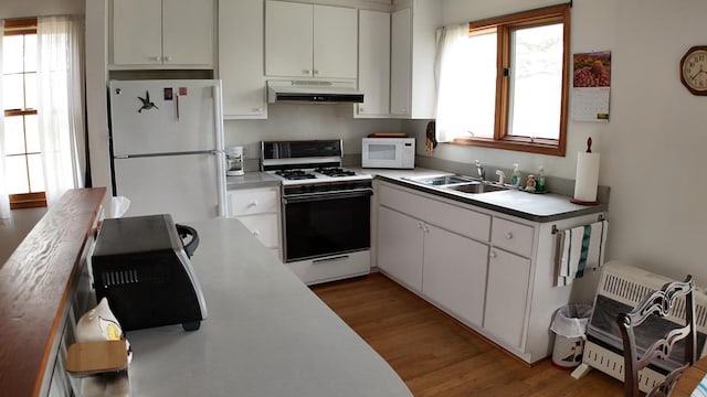 2012 Millenbeck Rd, Lancaster, VA 22503 - kitchen featuring light wood finished floors, a sink, a wealth of natural light, white appliances, and under cabinet range hood