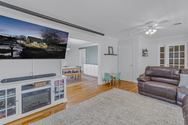 living room with crown molding, ceiling fan, and wood-type flooring