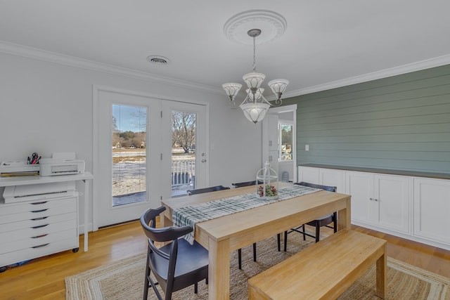 dining room with a notable chandelier, light hardwood / wood-style floors, and ornamental molding