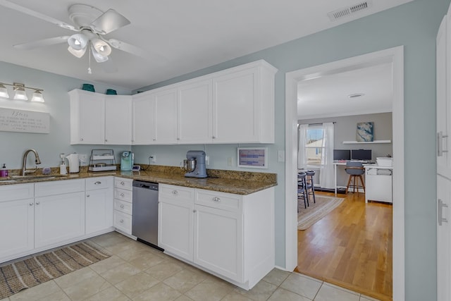 kitchen featuring white cabinetry, sink, light tile patterned floors, and stainless steel dishwasher