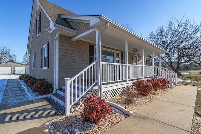 view of front of property with covered porch, a garage, and an outbuilding