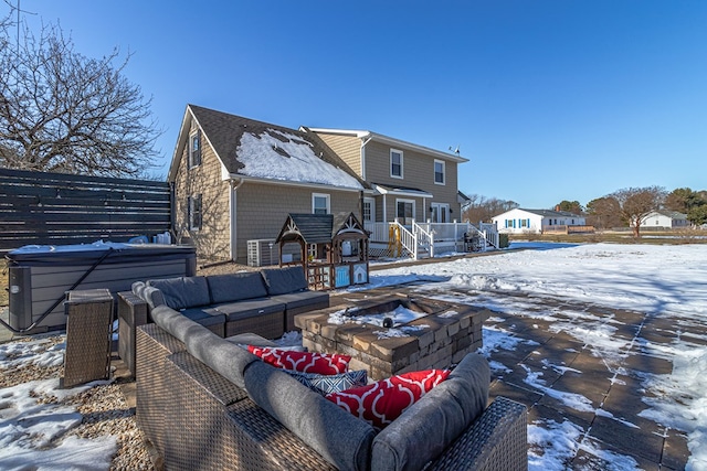 snow covered property featuring an outdoor living space with a fire pit and a hot tub