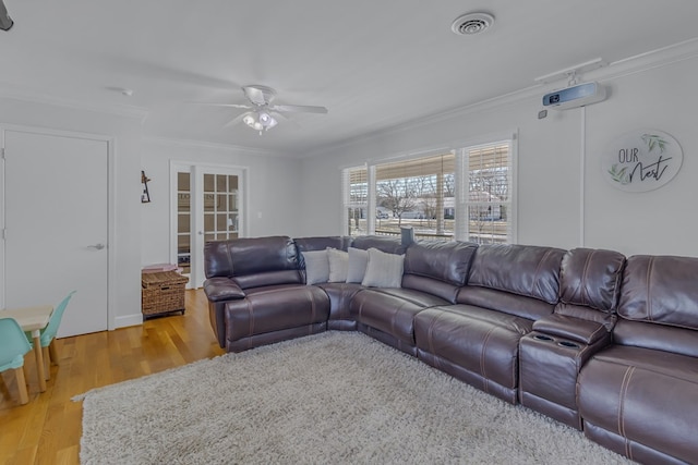 living room featuring ceiling fan, light wood-type flooring, ornamental molding, and french doors