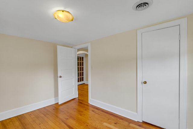 19 Wharton Grove Ln, Weems, VA 22576 - unfurnished bedroom featuring arched walkways and light wood-style flooring