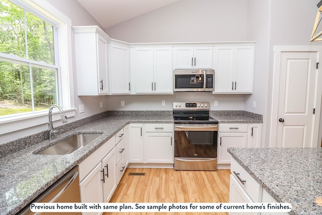 276 Safe Harbor Lndg, Hague, VA 22469 - kitchen featuring appliances with stainless steel finishes, lofted ceiling, light wood-style floors, white cabinetry, and light stone counters