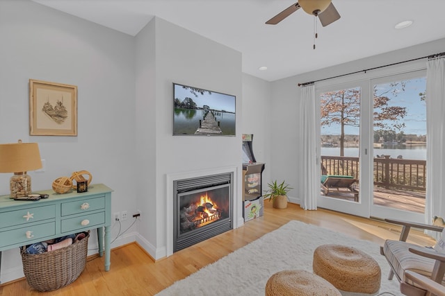 sitting room with ceiling fan, recessed lighting, baseboards, light wood-style floors, and a glass covered fireplace