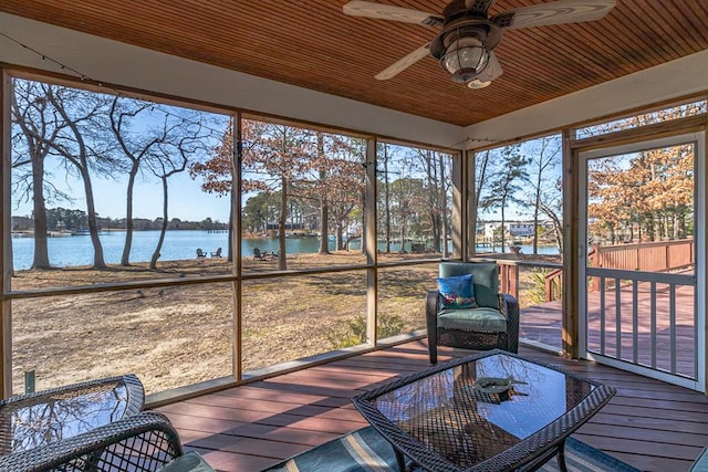 unfurnished sunroom featuring ceiling fan and a water view