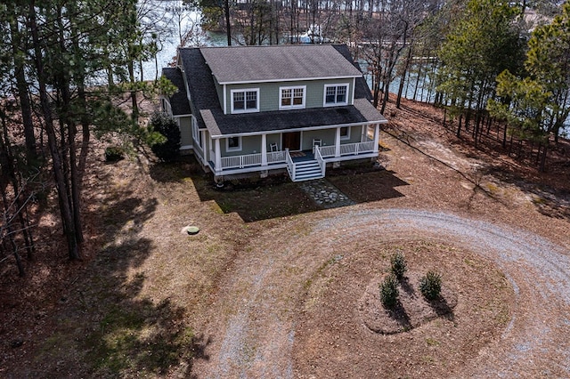 view of front of home with a porch, roof with shingles, and dirt driveway