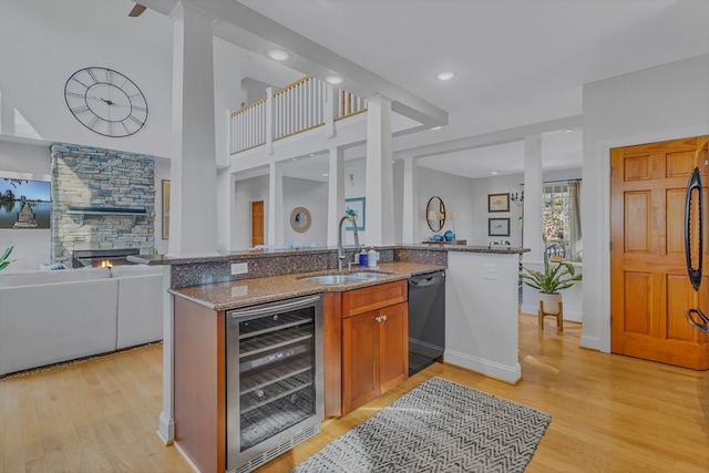 kitchen with wine cooler, a sink, black dishwasher, open floor plan, and dark stone countertops