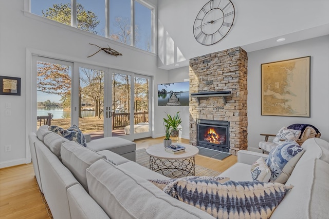 living room featuring a wealth of natural light, french doors, a fireplace, and wood finished floors