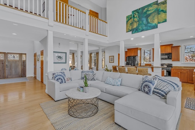 living room featuring light wood-type flooring, a towering ceiling, and recessed lighting