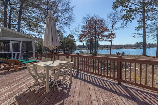 wooden terrace with outdoor dining space, a sunroom, and a water view