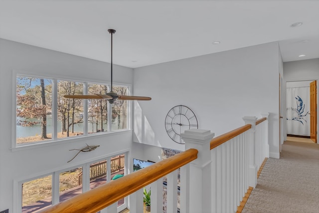 corridor featuring carpet, baseboards, and an upstairs landing