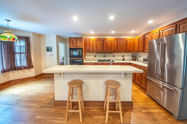 1851 Desha Rd, Tappahannock, VA 22560 - kitchen with black appliances, light wood finished floors, light countertops, a breakfast bar area, and brown cabinets