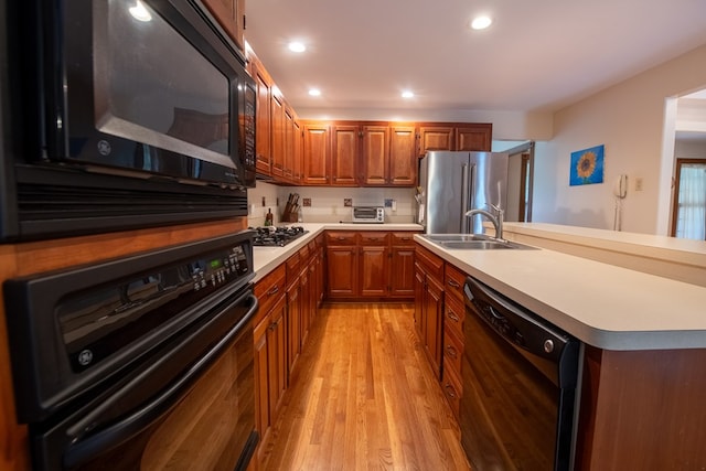 1851 Desha Rd, Tappahannock, VA 22560 - kitchen with black appliances, a sink, brown cabinets, light wood finished floors, and light countertops