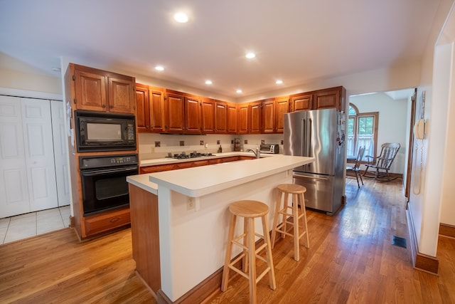 1851 Desha Rd, Tappahannock, VA 22560 - kitchen with black appliances, light countertops, light wood-style flooring, a kitchen bar, and recessed lighting